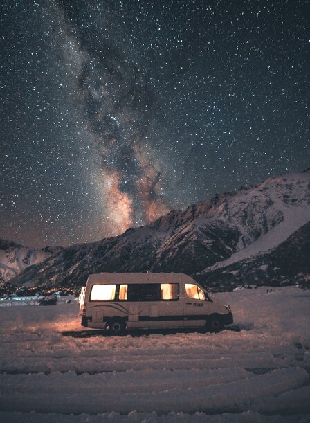 Camper van under a starry mountain sky